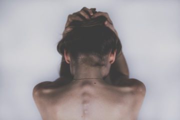 woman with back turned from camera holding her head